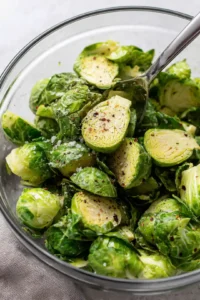 Toss halved Brussels sprouts with olive oil, balsamic vinegar, garlic powder, salt, pepper, and red pepper flakes until evenly coated