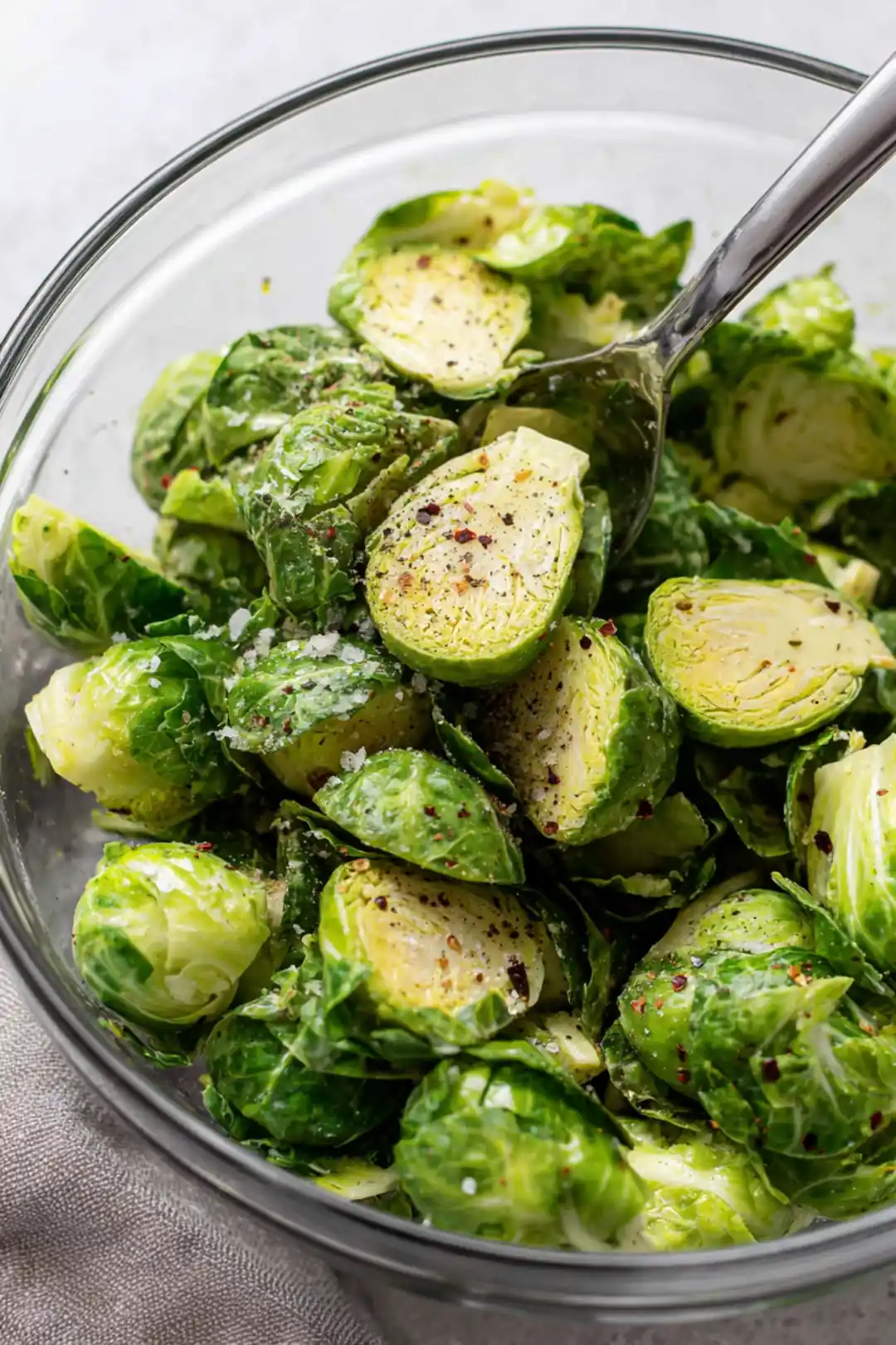 Toss halved Brussels sprouts with olive oil, balsamic vinegar, garlic powder, salt, pepper, and red pepper flakes until evenly coated