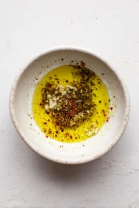 Mix together olive oil, minced garlic, lemon juice, salt, black pepper, and paprika
