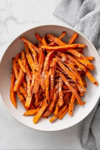 Toss sweet potato fries with olive oil, cornstarch, salt, garlic powder, and paprika until evenly coated