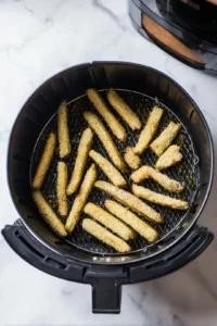 Arrange eggplant fries in air fryer and lightly spray with olive oil