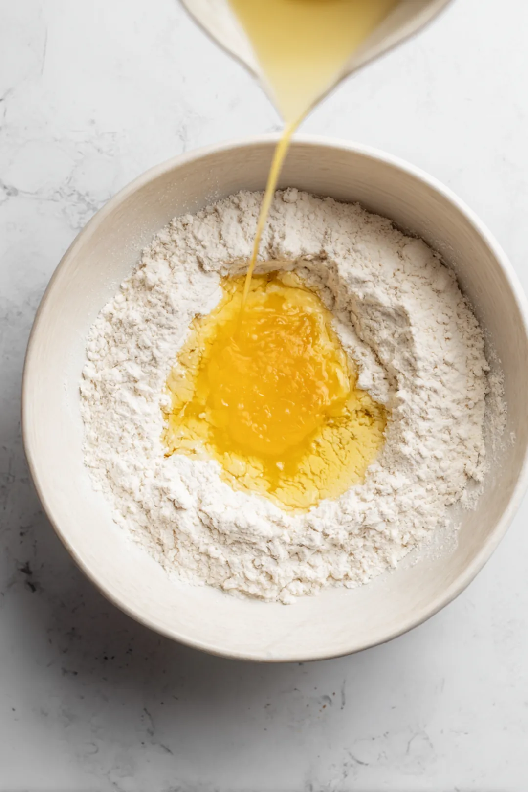 Gradually add lukewarm water and olive oil to the dry ingredients, mixing until a smooth dough forms. Let it rest for 15 minutes.