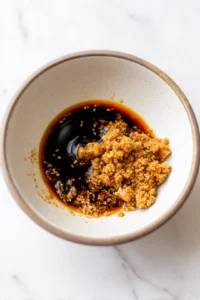 Mix together soy sauce, sesame oil, garlic powder, and ginger powder, then toss with diced tofu to coat and marinate.