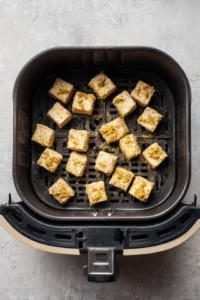 Coat marinated tofu with nutritional yeast and whole wheat flour