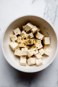Combine cubed tofu with seasonings in a mixing bowl