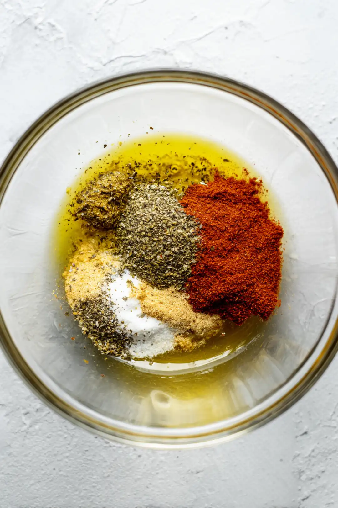 Combine olive oil, paprika, garlic powder, onion powder, salt, and black pepper to create a marinade and coat the chicken leg quarters thoroughly with this mixture