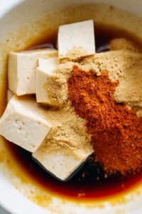Marinate the pressed tofu with soy sauce, garlic powder, onion powder, and paprika for 10 minutes