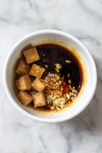 Marinate tofu cubes in a sticky sauce of soy sauce, maple syrup, garlic, and ginger for at least 15 minutes