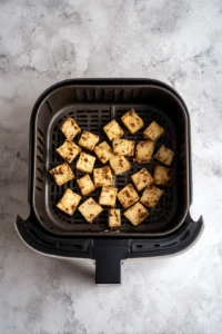 Preheat the air fryer to 375 degrees Fahrenheit. Place marinated tofu in air fryer and cook until golden and crispy.