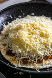 Add shredded cheese and taco meat to the tortilla