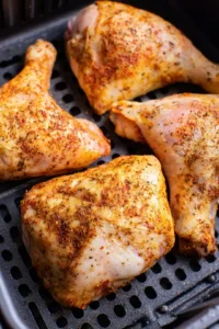 Cook seasoned chicken leg quarters in the air fryer until crispy