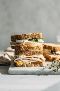 Layer bread, turkey, cheese, and seasoning to assemble the sandwiches