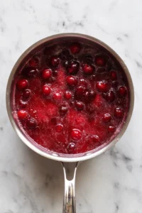 Simmer the mixture until cranberries burst
