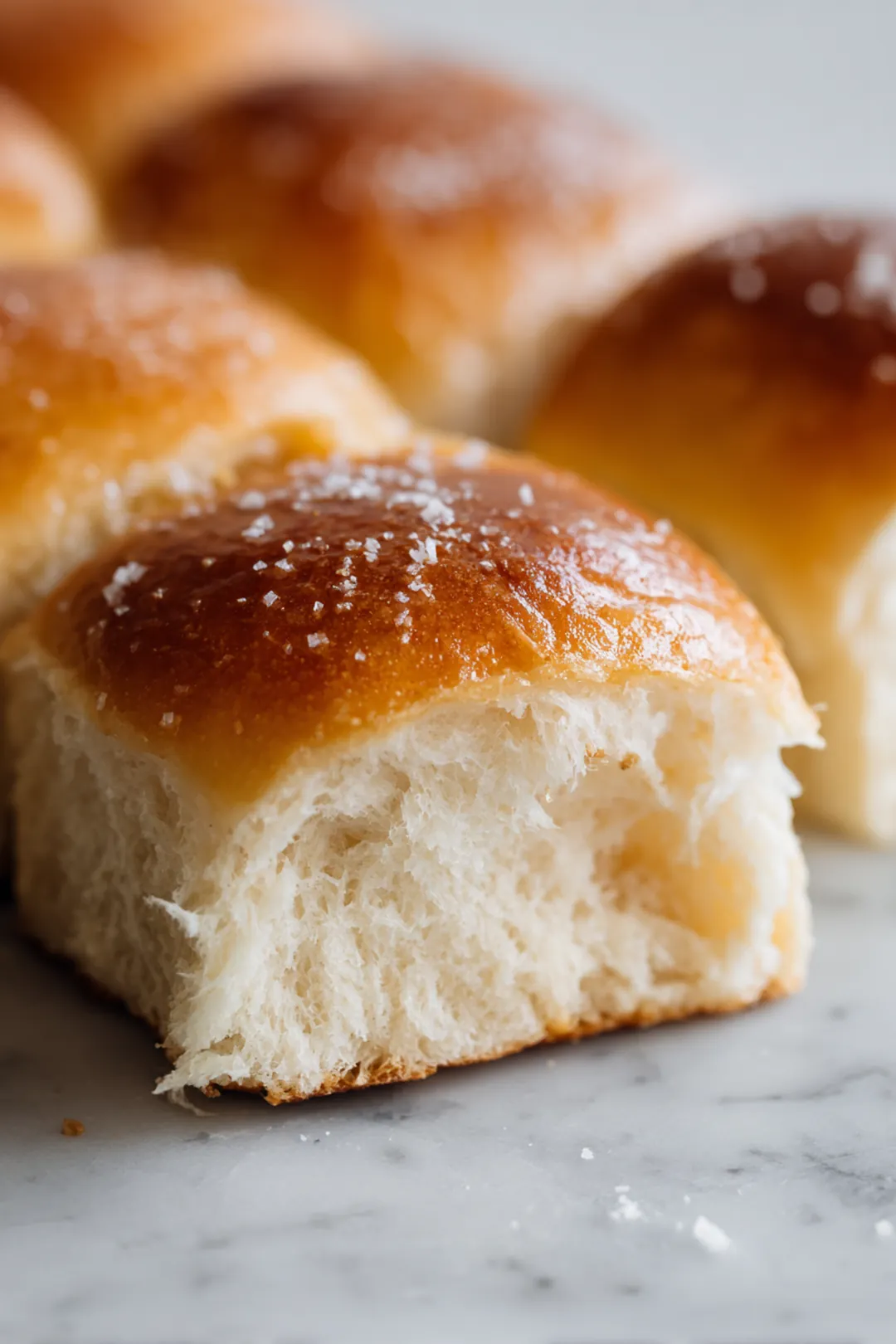 Slice the Hawaiian rolls in half horizontally, maintaining them in a single slab. Place the bottom halves in a baking dish.