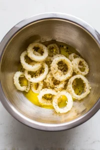 Toss frozen onion rings with olive oil in a mixing bowl