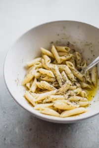 Toss the cooked pasta with olive oil, salt, garlic powder, and Parmesan cheese