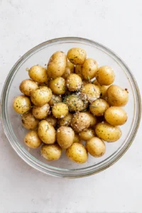 Add halved baby potatoes to the air fryer with olive oil and seasoned salt