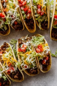 Assemble the taco with cooked smash burgers, shredded lettuce, diced tomatoes, and cheese