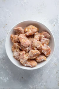 Coat the marinated chicken pieces in cornstarch to achieve a crispy texture.