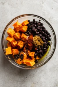 Combine diced sweet potatoes, black beans, olive oil, cumin, and paprika in a mixing bowl and toss to coat evenly