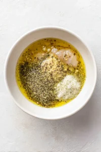Combine pickle juice, olive oil, garlic powder, and onion powder with chicken thighs in a bowl and marinate.