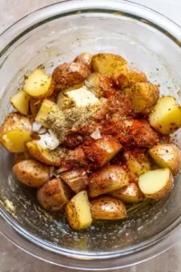 Combine potatoes, olive oil, garlic powder, paprika, salt, and pepper in a mixing bowl