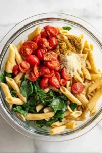 Combine the pasta, cherry tomatoes, spinach, olive oil, garlic powder, salt, and black pepper in a large bowl