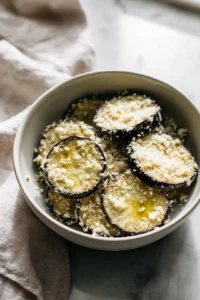 Dredge eggplant slices in almond flour and parmesan cheese mixture and arrange in air fryer basket