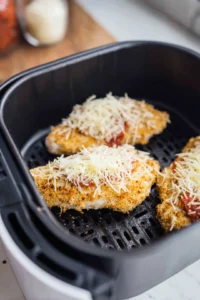 Flip the chicken, add marinara sauce and mozzarella cheese, and air fry