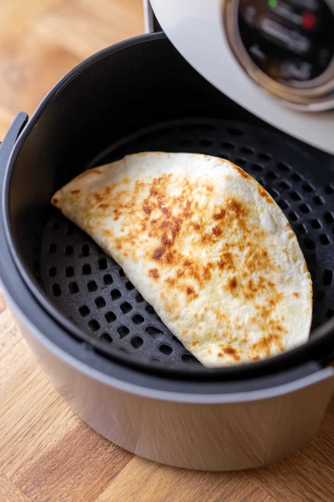 Fold the tortilla over to create a wrap and place it in the air fryer basket and cook until crispy and golden brown