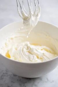 In a mixing bowl, beat the cream cheese until smooth and creamy. Add in the sugar, egg, vanilla extract, and sour cream, mixing until fully combined.