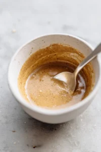 Mix tahini sauce, lemon juice, minced garlic, and water