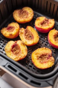 Place the coated peaches in the air fryer basket and cook for 10 minutes until tender and caramelized