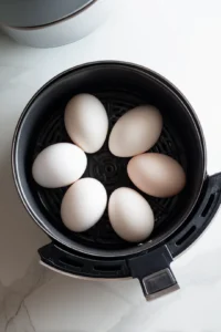 Place the eggs in the air fryer basket and add 1 cup of water to create steam. Cook for 10 minutes for perfect jammy eggs.