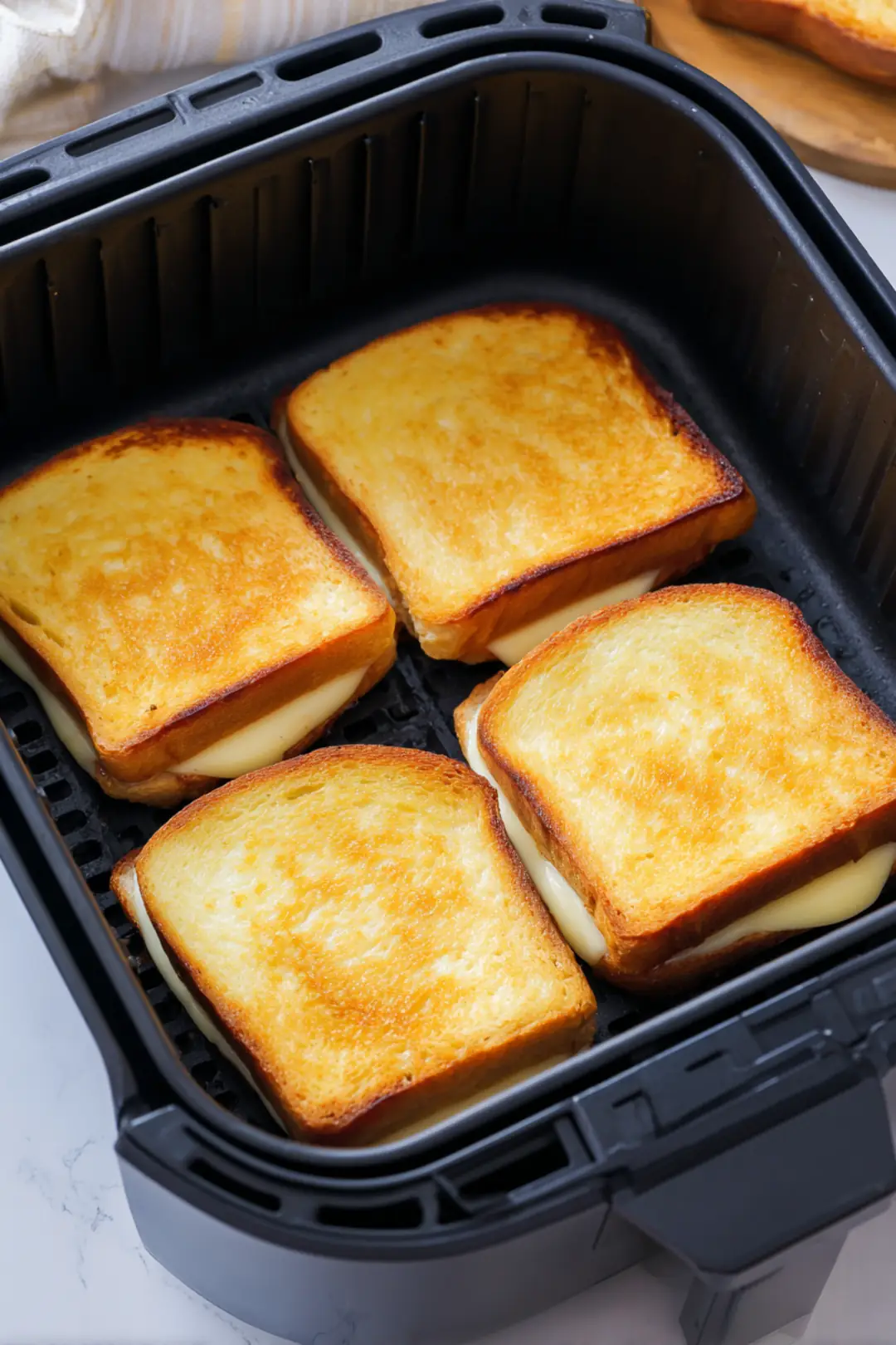 Place the sandwiches in the air fryer basket and cook at 360°F (180°C) for about 8-10 minutes until golden brown and the cheese has melted flipping halfway through if necessary.