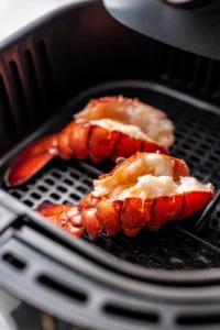 Preheat your air fryer to 380°F (193°C). While it preheats, prepare the lobster tails by cutting them down the center of the shell and pulling the meat slightly out for better cooking.