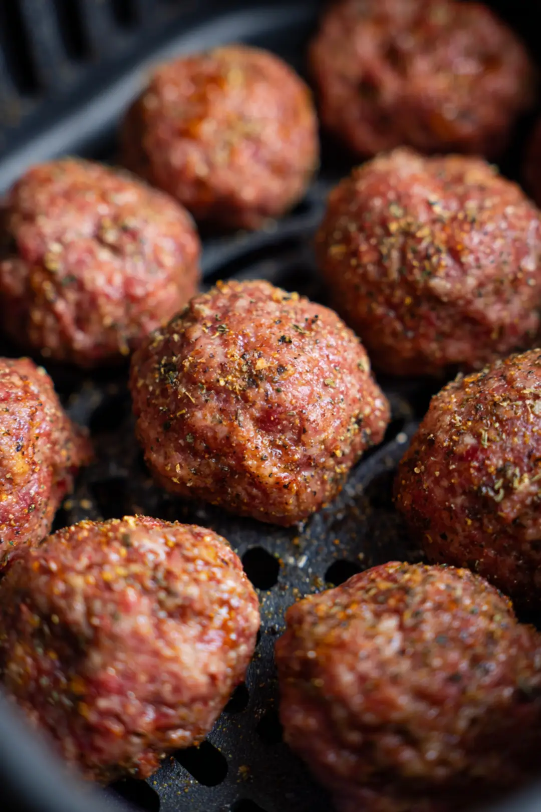 Shape the ground beef into small balls and season with burger seasoning. Place the meatballs in the air fryer and flatten them to create smash burgers.