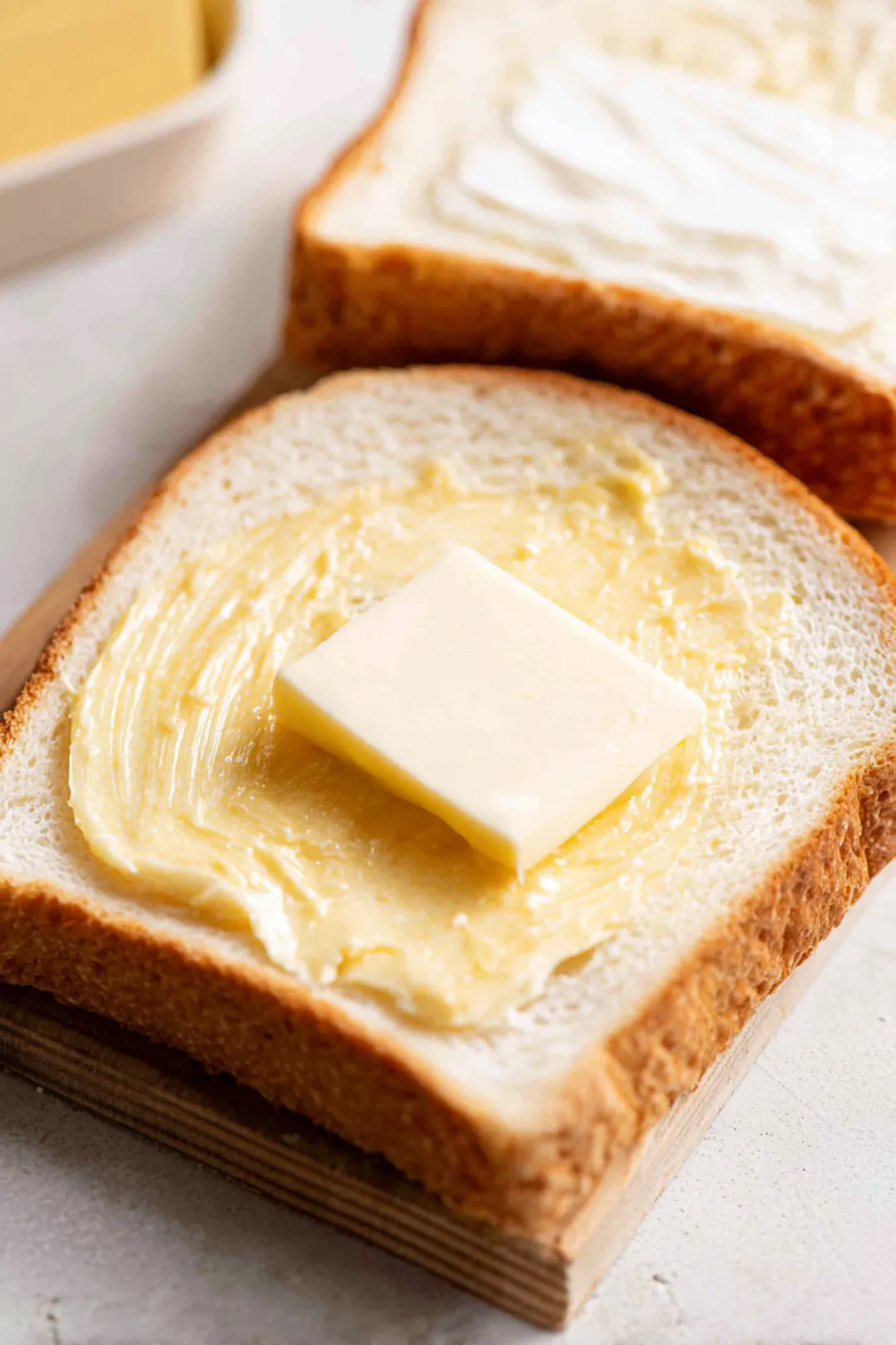 Spread butter on one side of each slice of bread and spread Dijon mustard on the unbuttered side of two slices