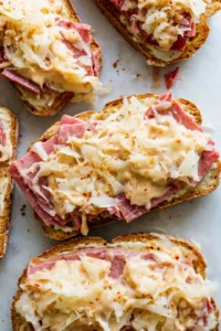 Assemble the sliders with thousand island dressing, corned beef, sauerkraut, and Swiss cheese