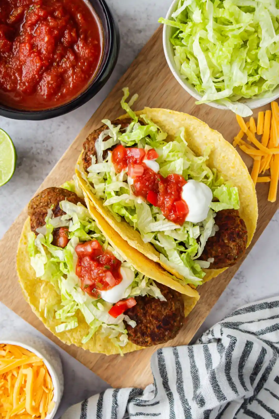 Assemble the tacos by placing a patty in each taco shell, then top with sour cream, salsa, shredded lettuce, and cheese.