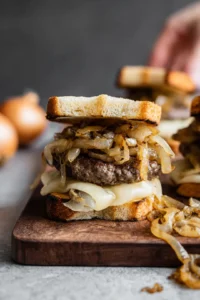 Assemble your patty melt by layering a beef patty on a slice of bread, topping it with caramelized onions and cheese, and then placing another slice of bread on top.