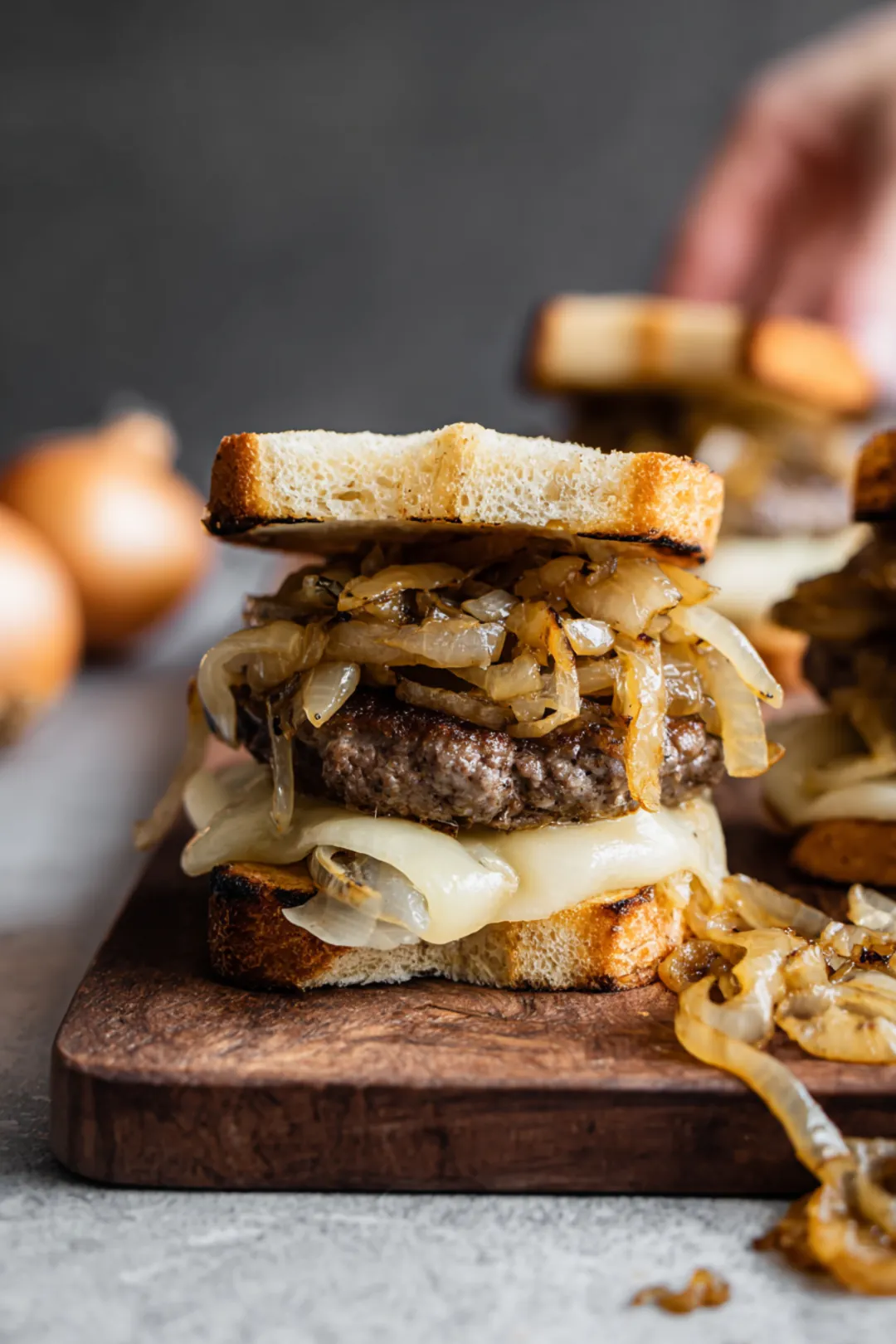 Assemble your patty melt by layering a beef patty on a slice of bread, topping it with caramelized onions and cheese, and then placing another slice of bread on top.