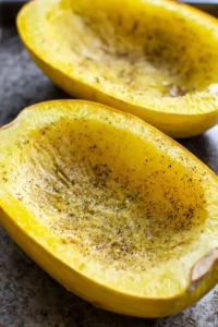 Brush cut sides of spaghetti squash with olive oil and season with salt, pepper, garlic powder, and Italian seasoning