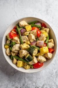 Combine chicken, vegetables, olive oil, and spices in a bowl