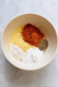 Combine cornmeal, all-purpose flour, paprika, garlic powder, salt, and black pepper in a mixing bowl