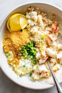 Combine crab meat, mayonnaise, beaten egg, breadcrumbs, Old Bay seasoning, chopped green onions, lemon juice, and black pepper