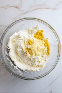 Combine cream cheese, cheddar cheese, and garlic powder in a mixing bowl and mix until well blended