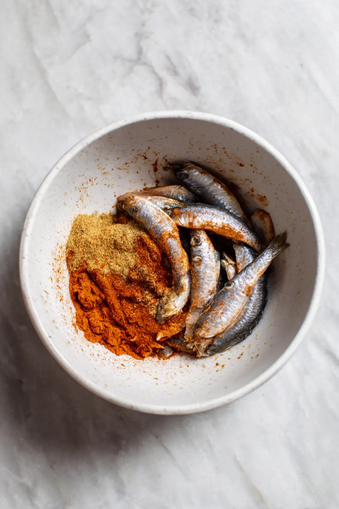 Combine drained sardines and tuna with garlic powder and paprika in a mixing bowl