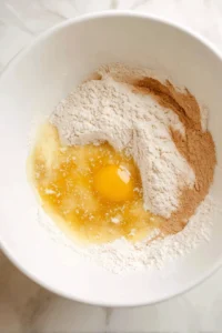 Combine flour, sugar, and cinnamon with melted butter, egg, and wine or vinegar to create a smooth dough