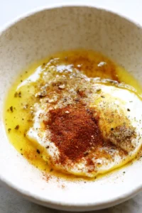 Combine Greek yogurt, olive oil, garlic powder, paprika, salt, and black pepper to create a marinade